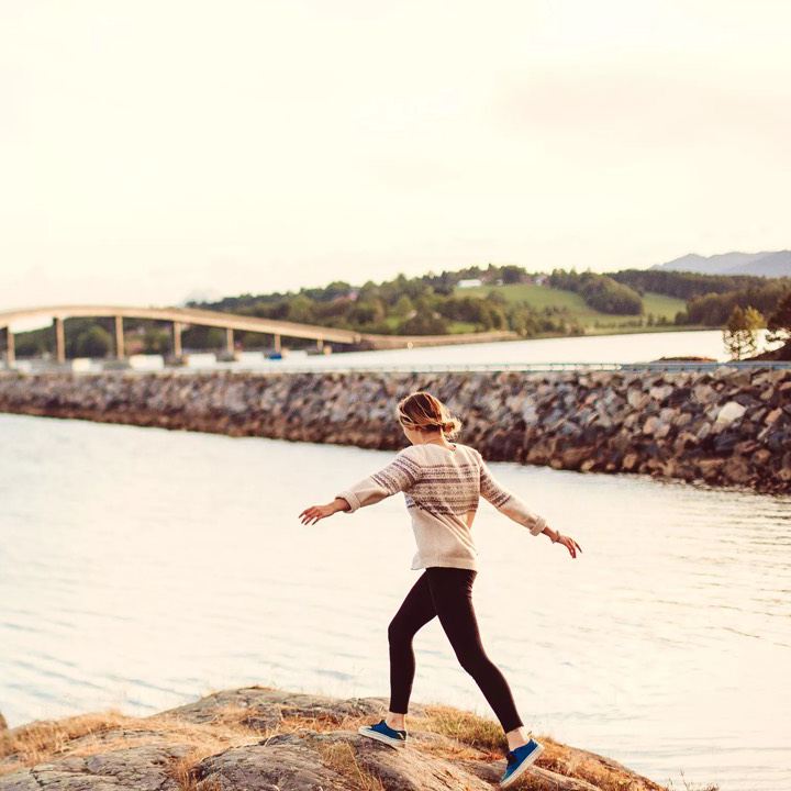 Chica caminando por unas rocas junto al mar