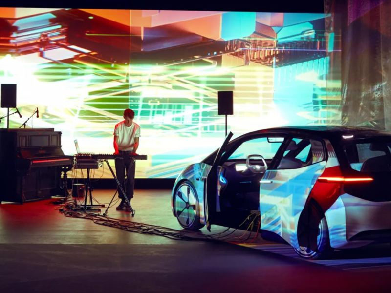 DJ en un escenario con un Volkswagen ID. 3 blanco y luces de colores