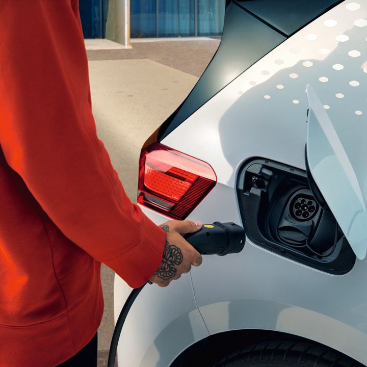 Detalle de la mano de una mujer conectando un cargador eléctrico a un Volkswagen ID.3