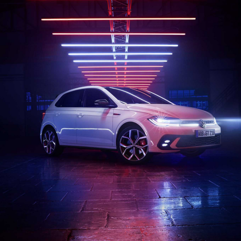 Un Volkswagen Polo GTI blanco bajo tubos de neón