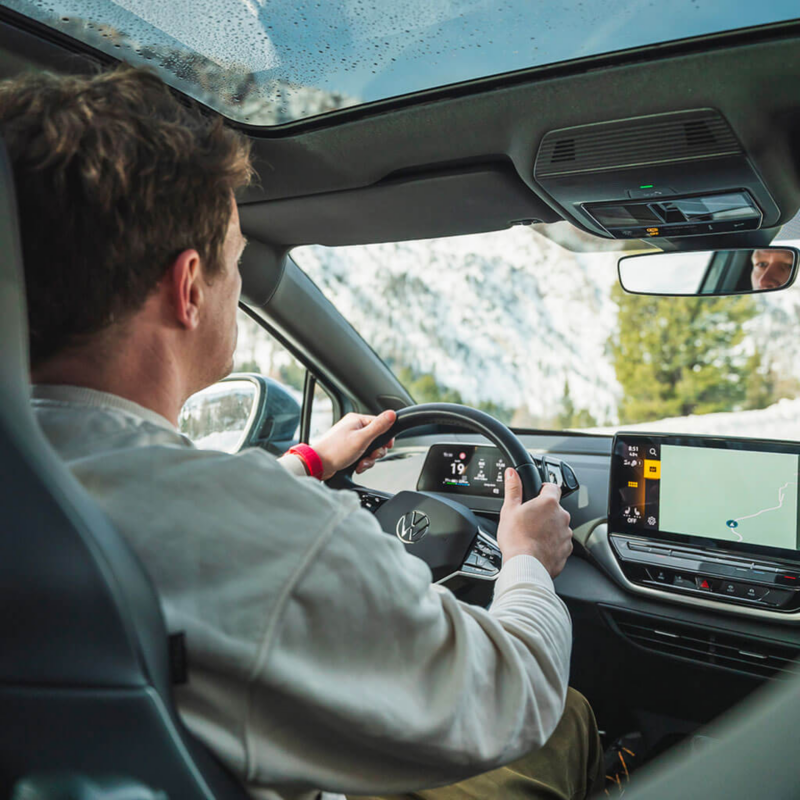 Vue d'un homme conduisant sa Volkswagen, depuis l'arrière du véhicule.