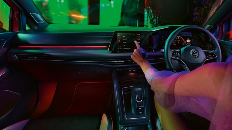 VW Golf GTI interior, cockpit view, woman operating infotainment system
