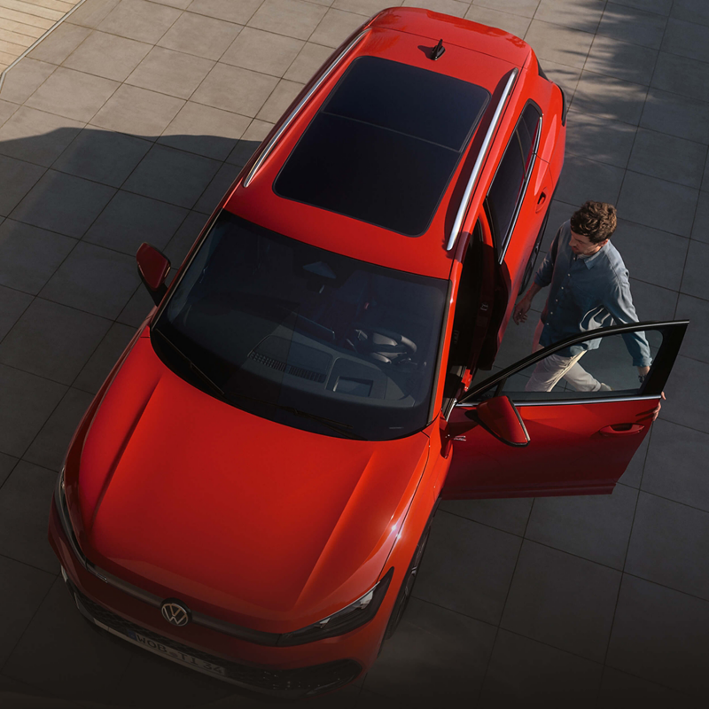An aerial shot of a man entering a red VW