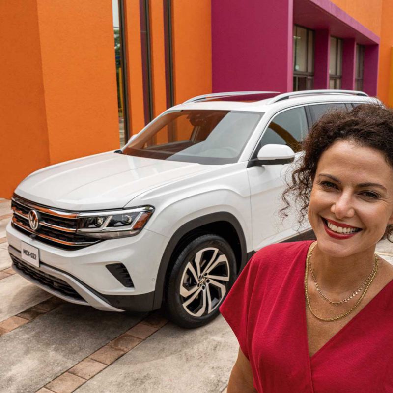 Camionetas de lujo de Volkswagen - Teramont 2022 y Cross Sport 2022. Mujer frente a camioneta blanca sonríe.