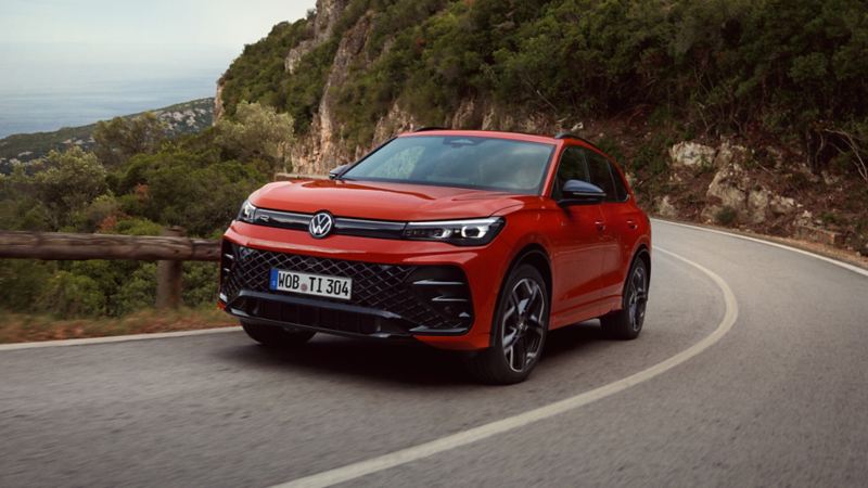 Front three-quarter view of red Tiguan driving on mountain road