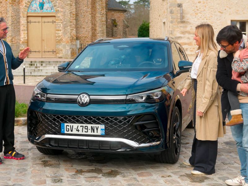 Le tone et une famille entoure le VW Tiguan vu de face.