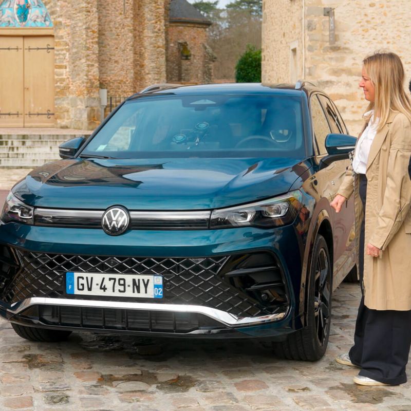 Le tone et une famille entoure le VW Tiguan vu de face.