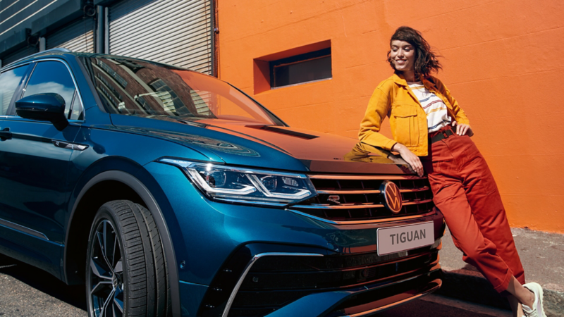 Eine Frau lehnt an den neuen Tiguan