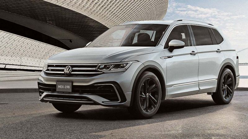 Tiguan 2023 en color gris circula frente a edificio moderno en distrito corporativo.