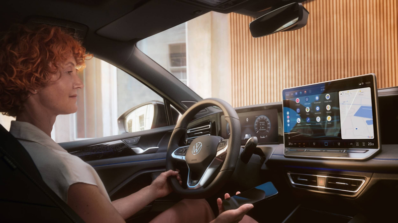 A woman in the driver's seat of a VW looking at the multimedia display
