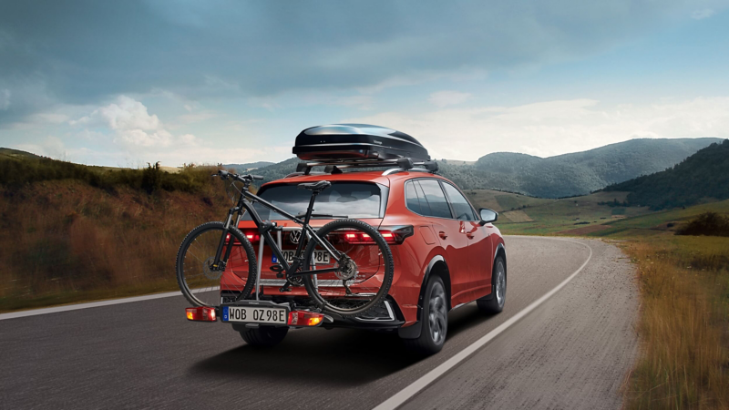 A read view of a VW Tiguan driving along a country road with a bike on the back