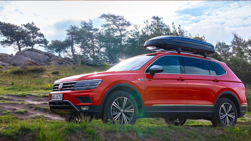 Tiguan rouge en circulation avec un coffre de toit.