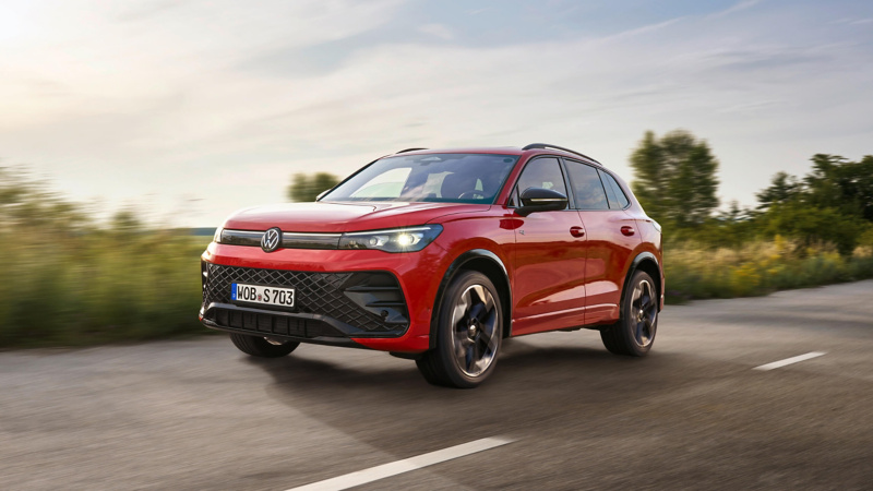 A red VW Tiguan driving along a country road