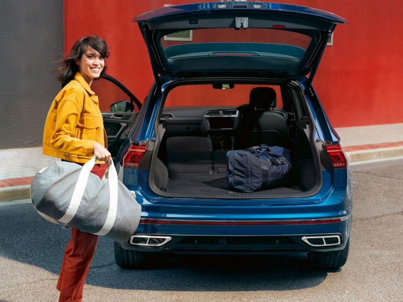 Woman with sports bag on open tailgate of VW Tiguan