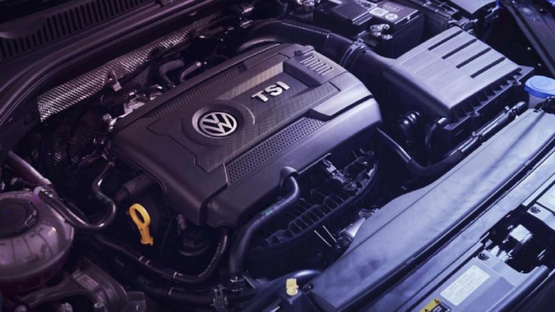 Motor de auto Volkswagen con protector de plástico y relieves de logo VW y TSI.