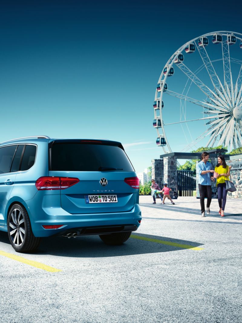 Blå VW Touran holder parkeret foran karrusel, ses bagfra