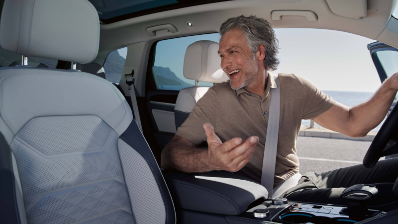 A man in the driver's seat of a VW Touareg smiling and looking behind him