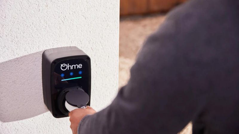 A man plugging a charger into an Ohme wallbox
