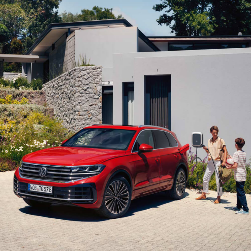 Touareg eHybrid rouge stationné devant une maison.