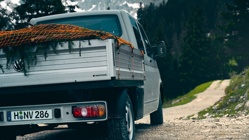 Ein beladener Transporter 6.1 Pritschenwagen auf einem Bergweg.