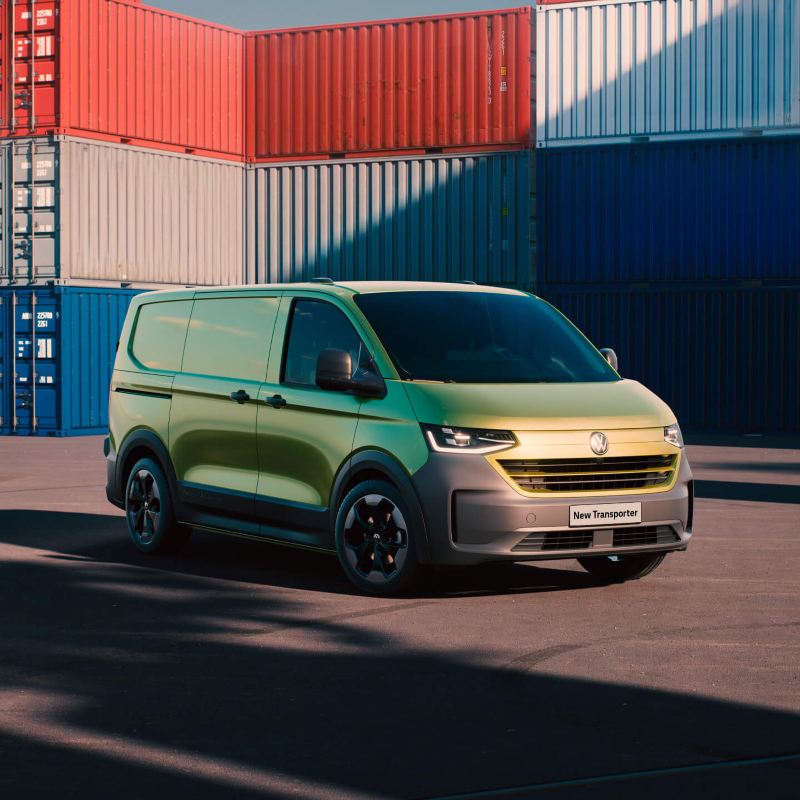 Photo of the New Transporter parked in front of towers of sea containers. 