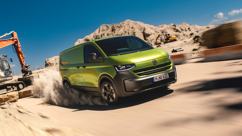 Nya VW Transporter kör genom grus på en byggarbetsplats.