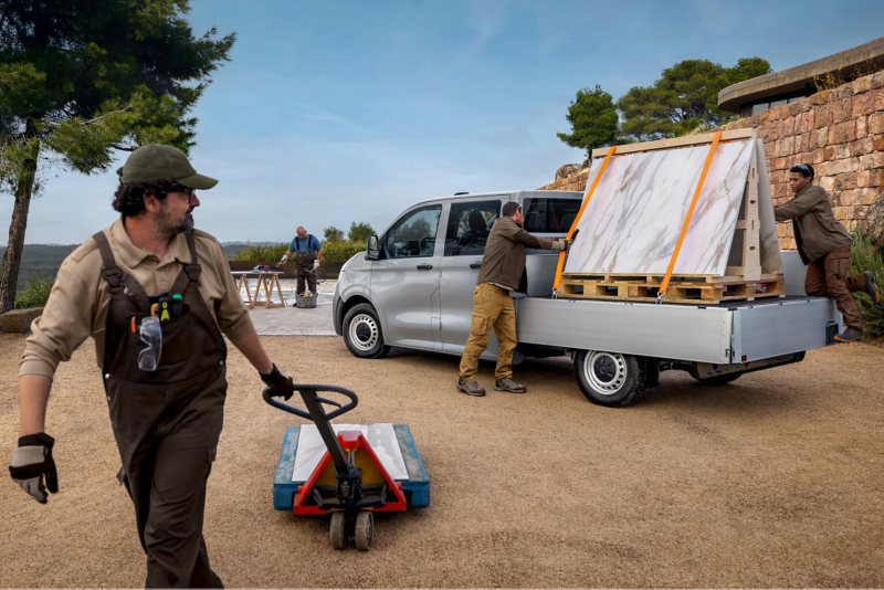 Handwerker verzurren eine Marmorplatte auf der Ladefläche des VW Pritschenwagen.