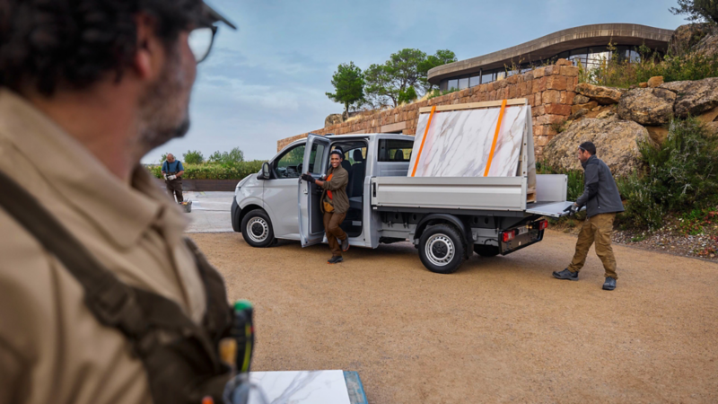 Intérieur d’un Volkswagen Transporter avec une banquette arrière spacieuse, une personne assise tenant une gourde.