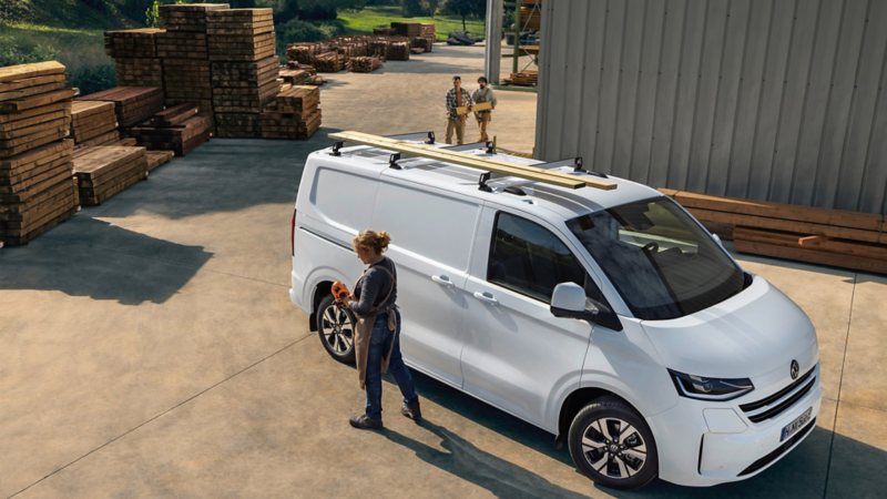 En kvinna går bredvid en VW Transporter Skåp