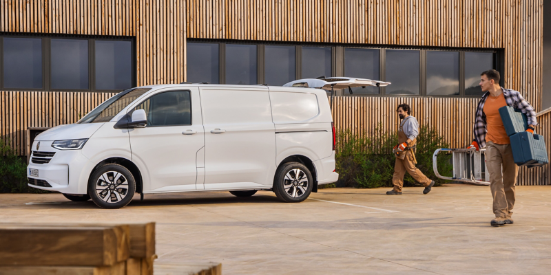 Handwerker entladen ihr Material aus einem VW Transporter Kastenwagen.