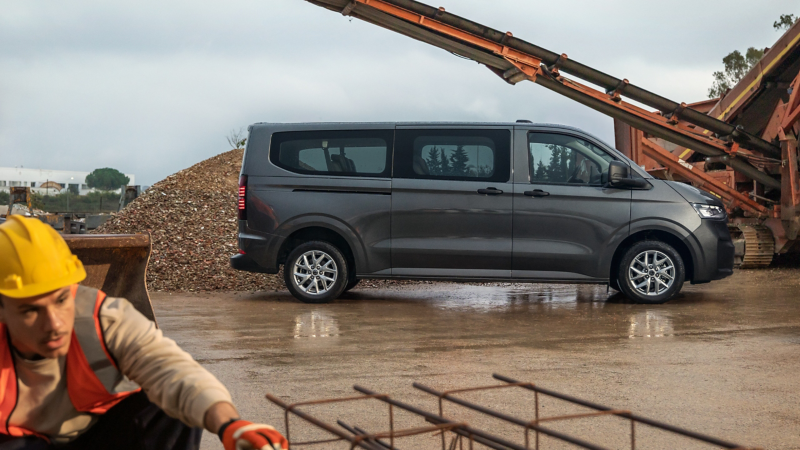 Transporter Kombi parkt auf einer Baustelle. Im Vordergrund ein Bauarbeiter.