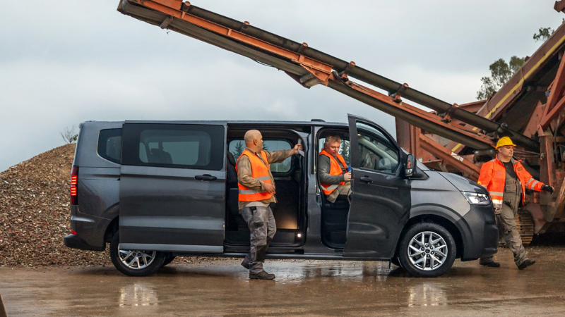 Mehrere Bauarbeiter steigen aus einem VW Transport Kombi.