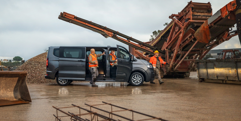 Bauarbeiter steigen aus deinem VW Transporter Kombi aus, im Hintergrund eine Baustelle mit großen Maschinen.