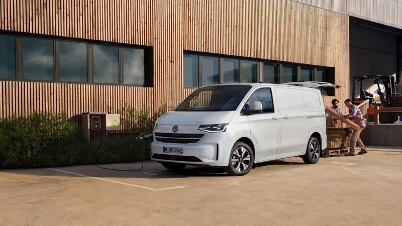 VW Transporter Kastenwagen eHybrid wird mit Holzbalken beladen.