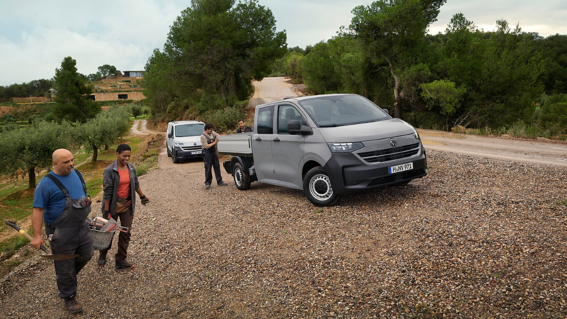 Deux Volkswagen Transporter plateau sur un chemin de gravier, l’équipe se rend au travail avec ses outils.