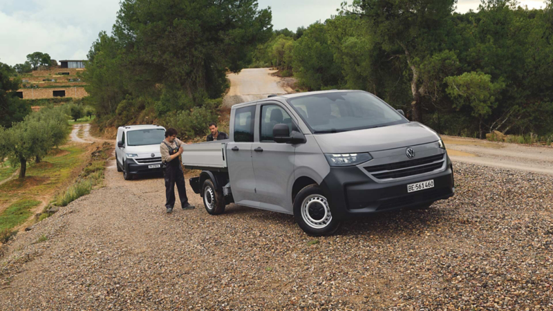 VW Transporter à plateau Entry sur route en gravier avec deux ouvriers
