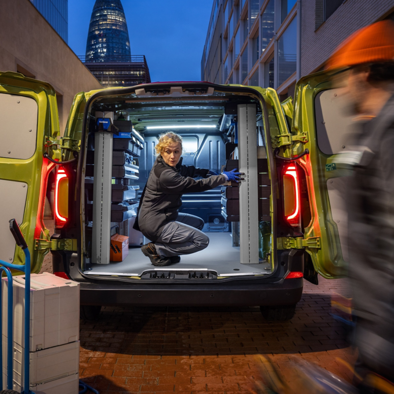 Pracownicy serwisu rozładowują materiały z VW Transportera Furgon z regałami Sortimo.