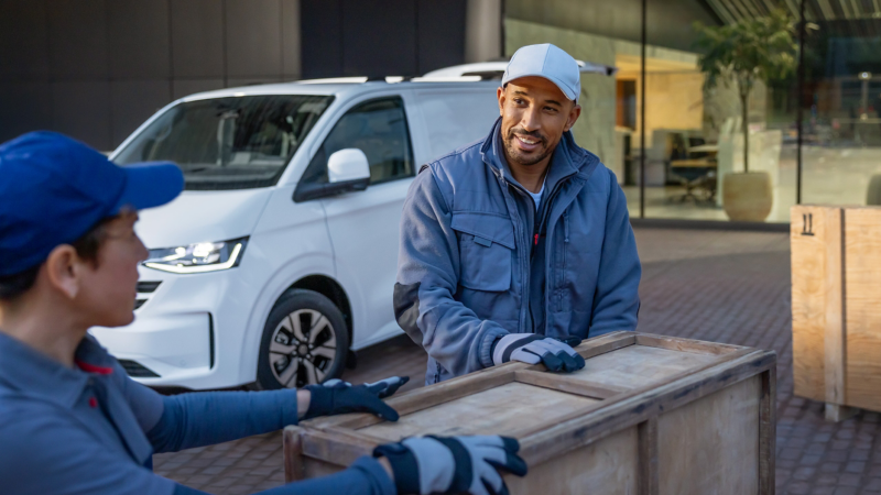 VW Transporter Kastenwagen wird von Spediteuren mit Kisten beladen.