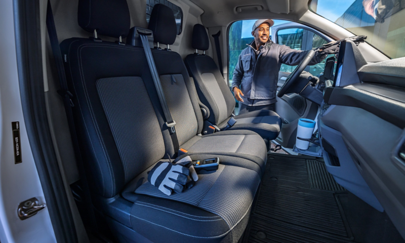 En arbeider legger noen arbeidshansker inn i vw transporter