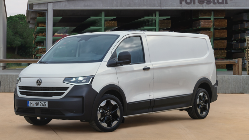 VW Transporter Kastenwagen parkt vor einem modernen Gebäude.