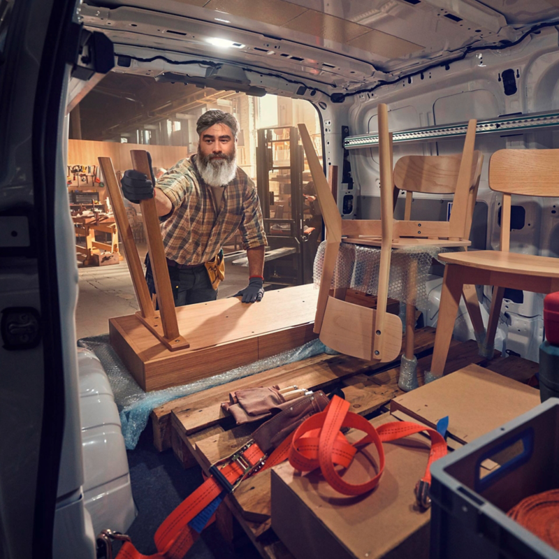 Ein Tischler verstaut Holzmöbel in einem VW Transporter.