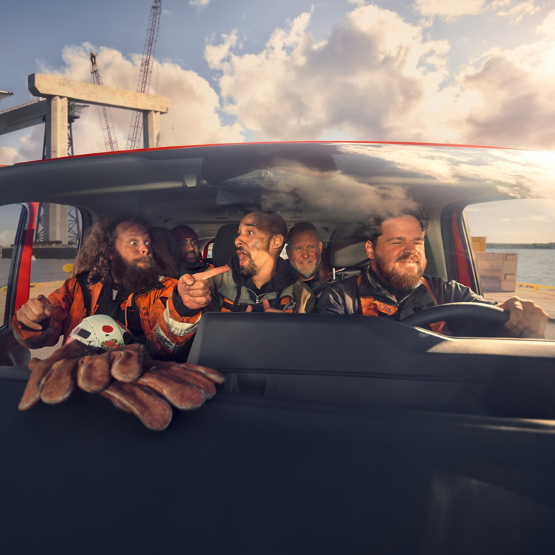 Handwerker sitzen lachend in einem VW Transporter Kombi.