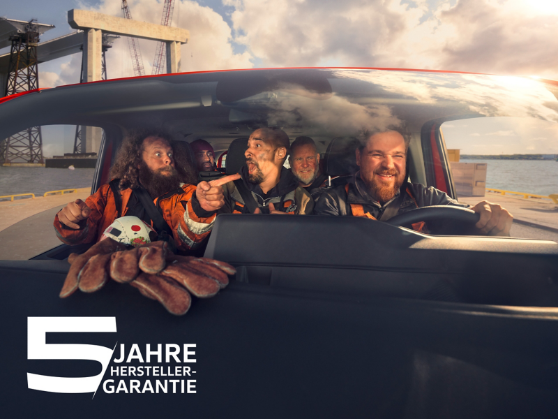 Mehrere Bauarbeiter sitzen in einem VW Transporter und machen scherze. Zusätzlich sist noch das Logo der 5 Jahre Herstellergarantie zu sehen.