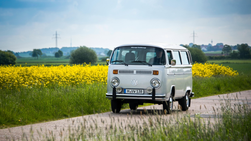 Ein alter VW Bus fährt eine Landstraße entlang.