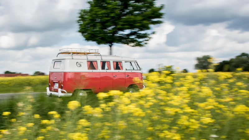 Ein alter VW Bus fährt eine Landstraße entlang.