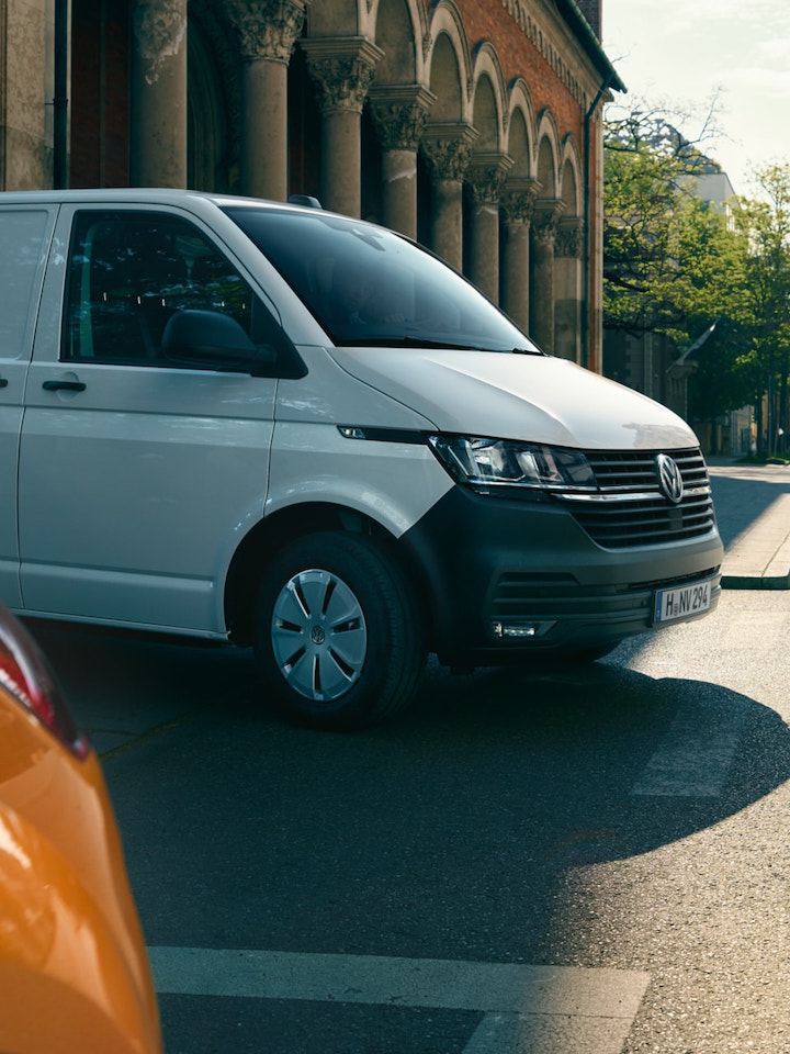 Volkswagen Transporter si sta immettendo in una strada, uscendo da un edificio. 