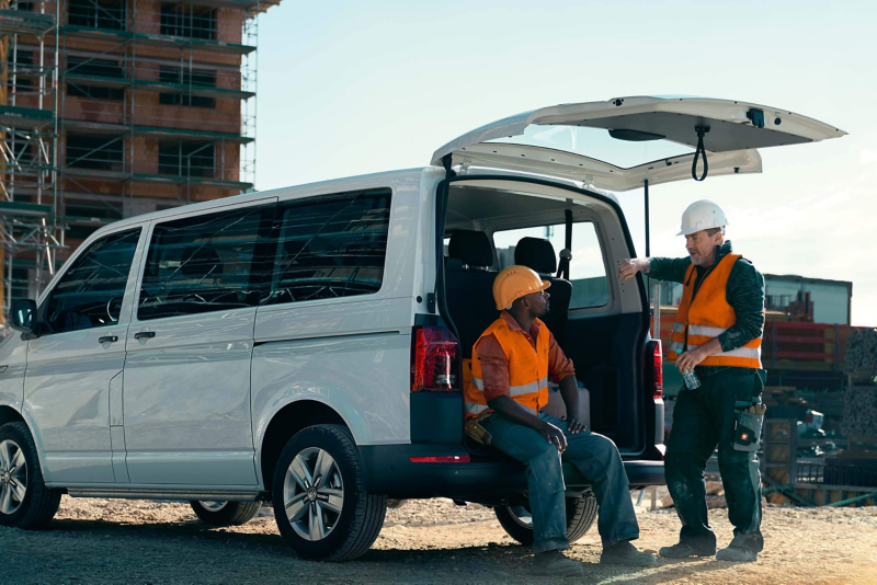 Deux ouvriers du bâtiment font une pause avec le coffre d'un Transporter Volkswagen ouvert.