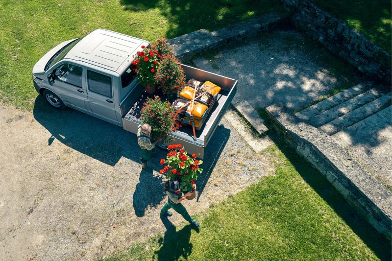Ein VW Transporter Pritschenwagen beladen mit Blumen und Blumenerde von oben.