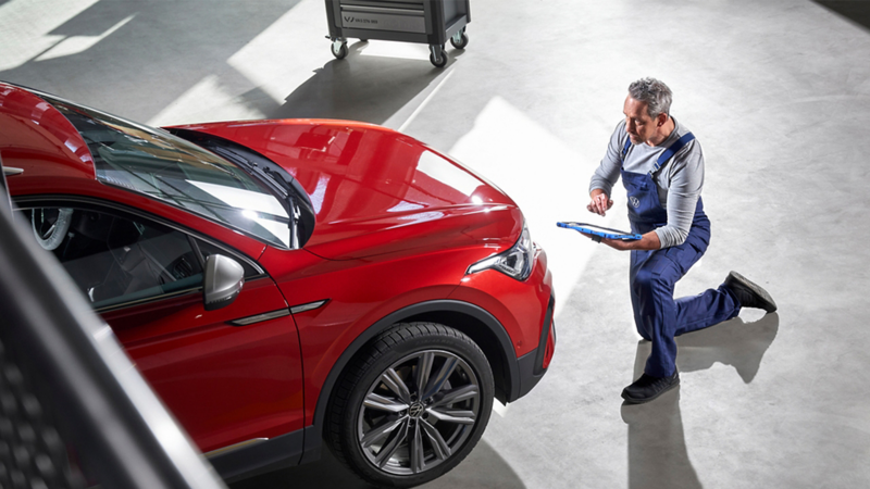 Mechanic inspecting bonnet of Volkwagen Car