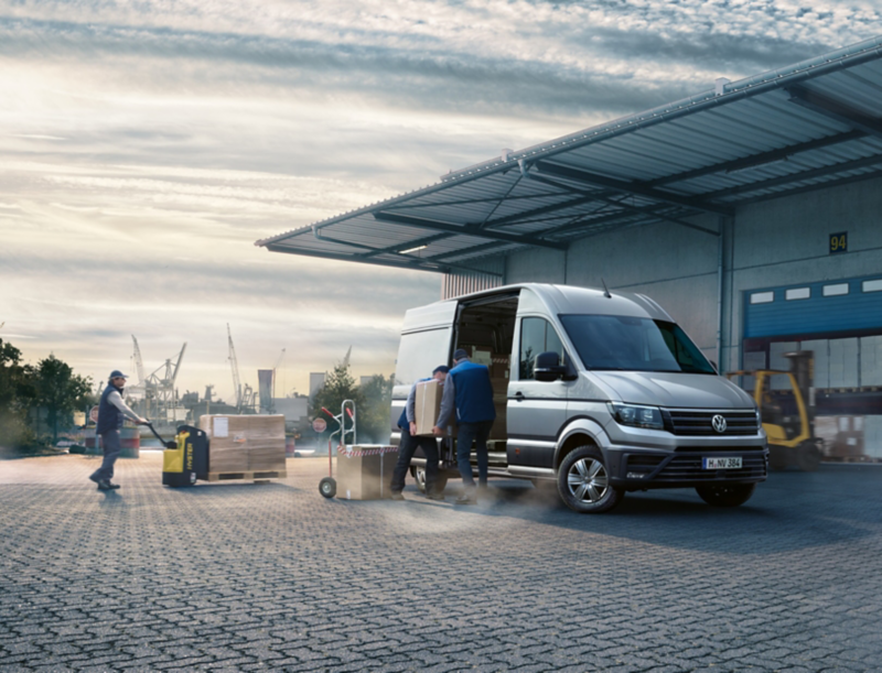 Mannen laden dozen in grijze Volkswagen Crafter